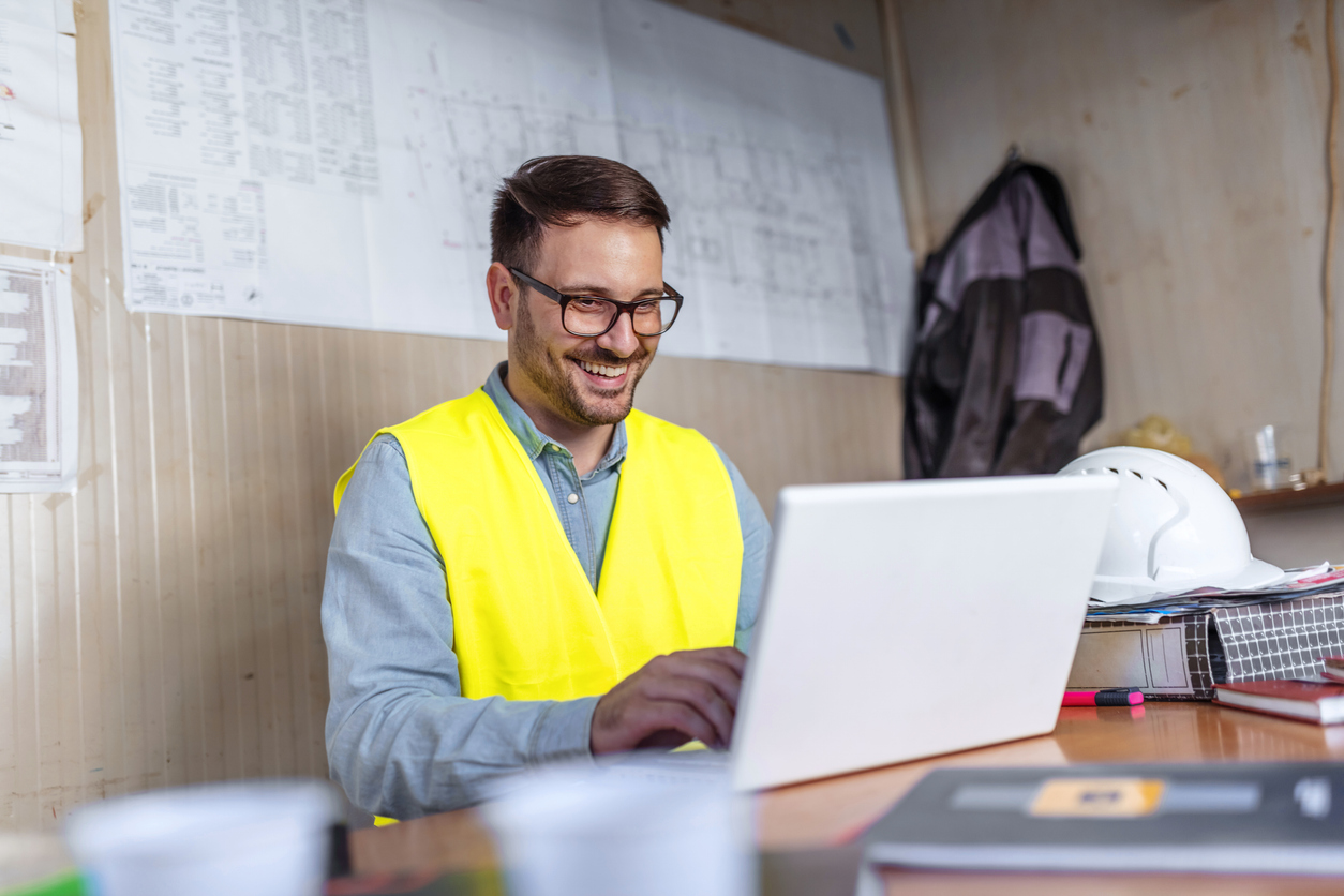 Man with a safety vest on laptop filling out form