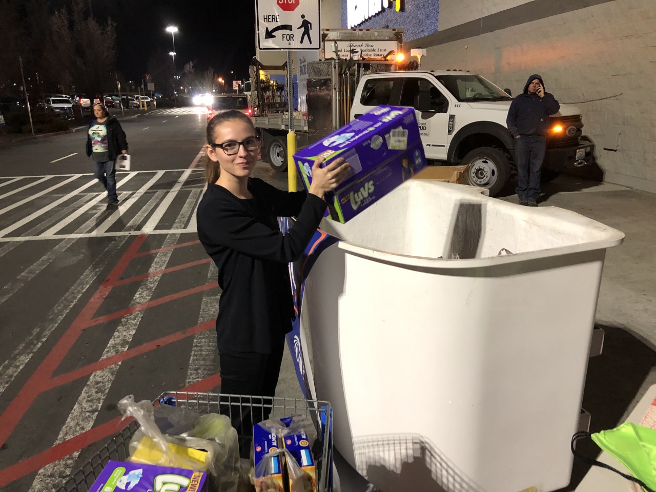 Woman putting boxes into a line truck bucket outside of Walmart.